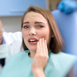 Woman in dental chair holding cheek