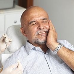 Man in dental chair holding jaw